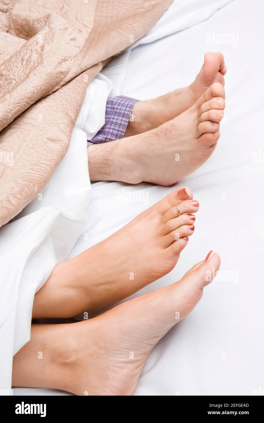 Primo piano di coupleÅ½s piedi sul letto Foto Stock
