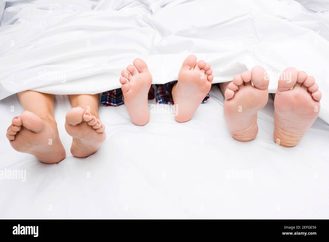 Primo piano di un coupleÅ½s piedi con il loro bambino sul letto Foto Stock