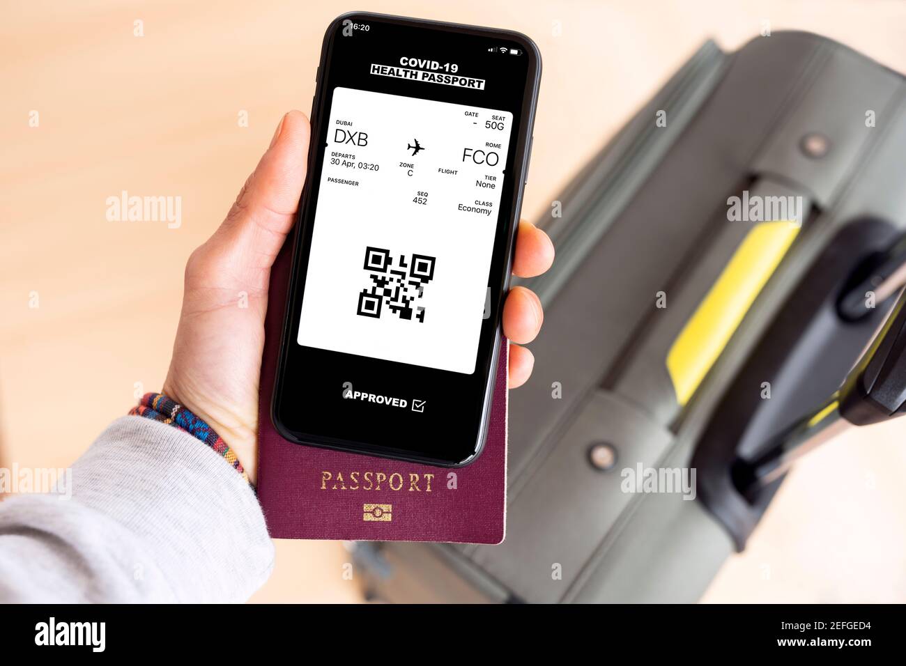 Vista dall'alto di una mano umana che tiene un passaporto e. uno smartphone con passaporto sanitario digitale con un carta d'imbarco Foto Stock