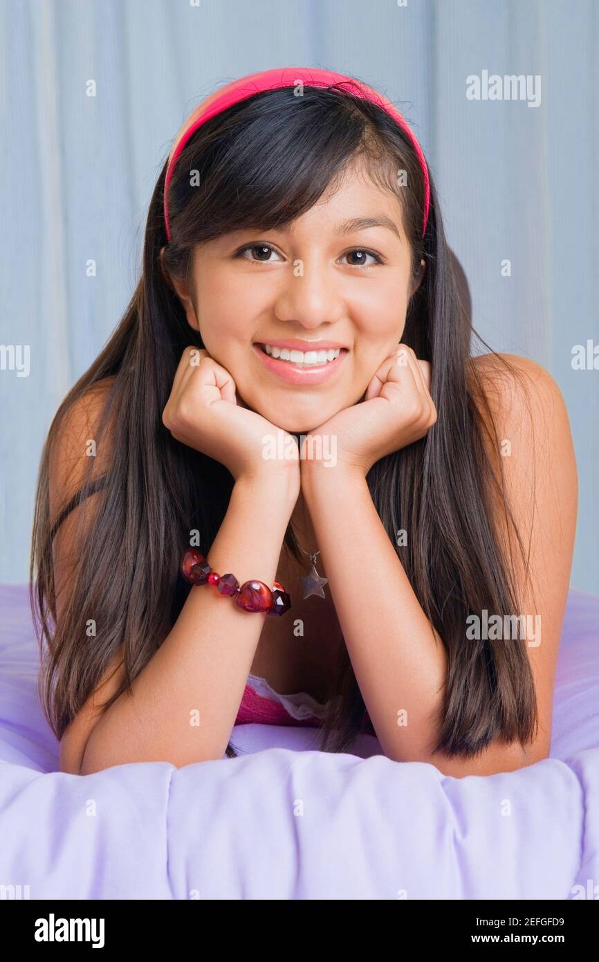 Ritratto di una ragazza adolescente giacente sul letto e sorridente Foto Stock