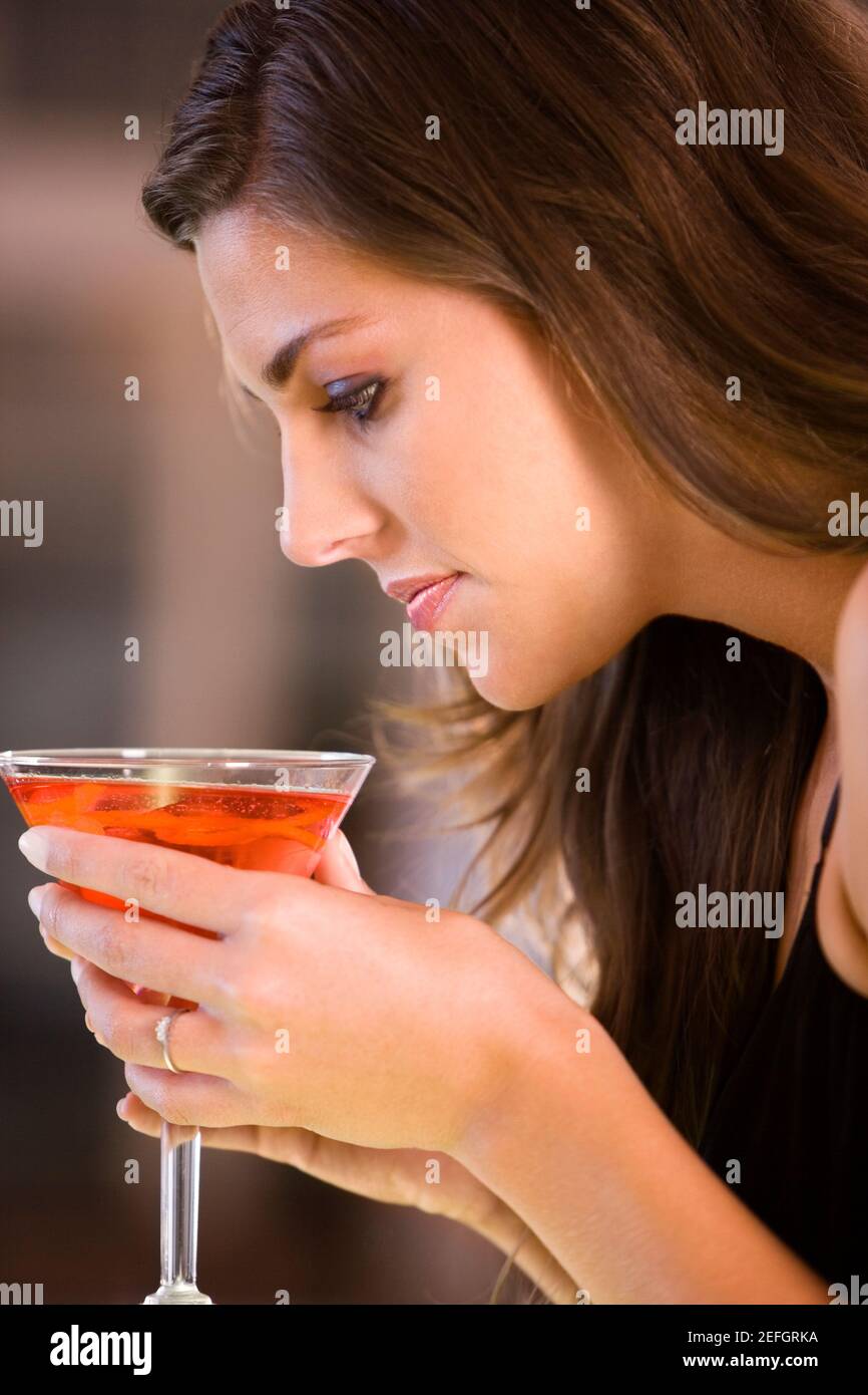 Profilo laterale di una giovane donna con in mano un bicchiere di martini Foto Stock