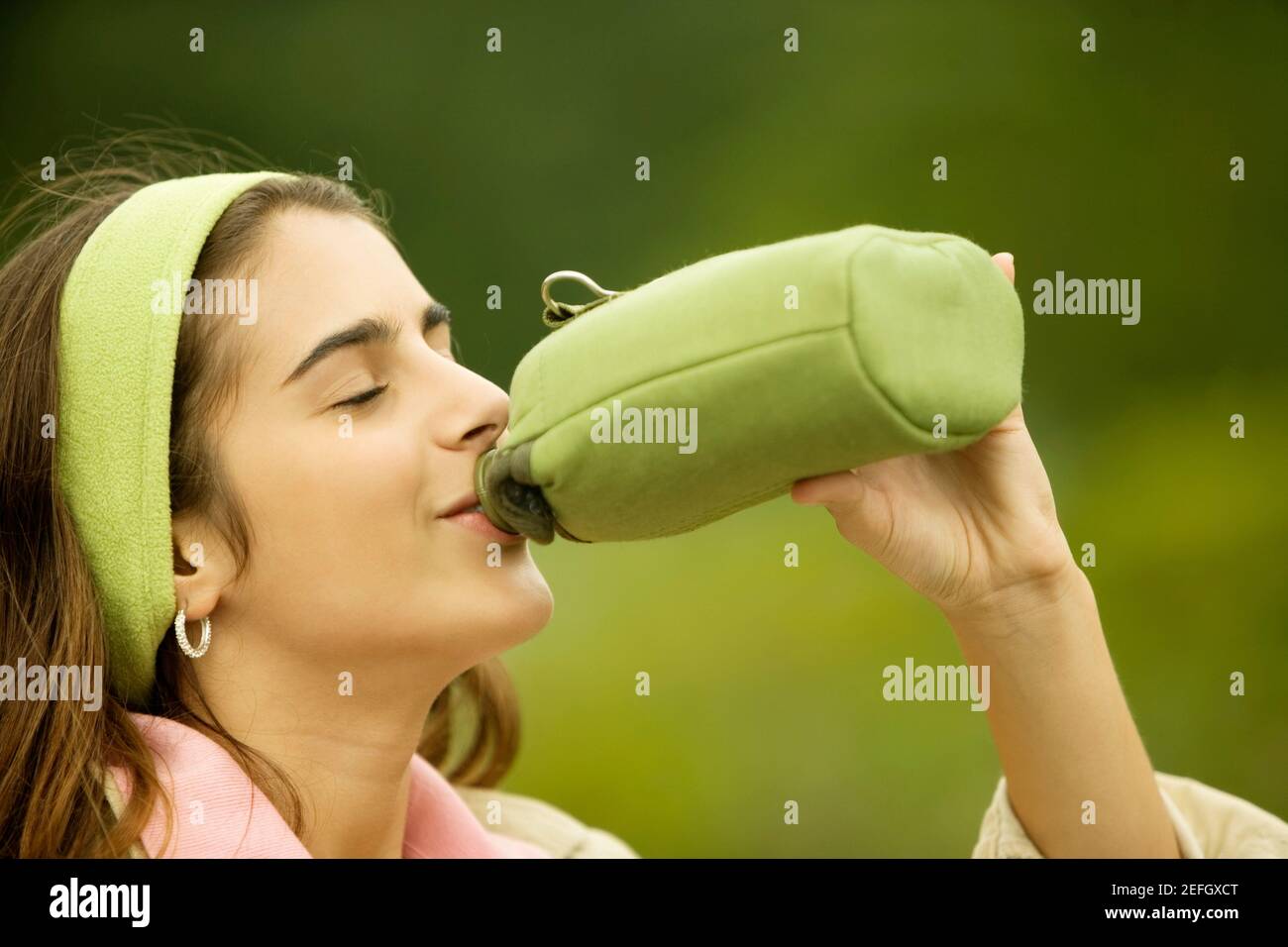 Profilo laterale di una ragazza che beve acqua da una bottiglia Foto Stock