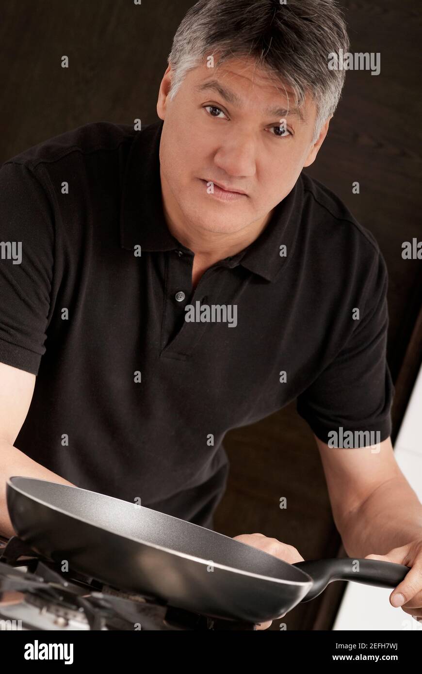 Ritratto di un uomo anziano che tiene una padella in padella la cucina Foto Stock