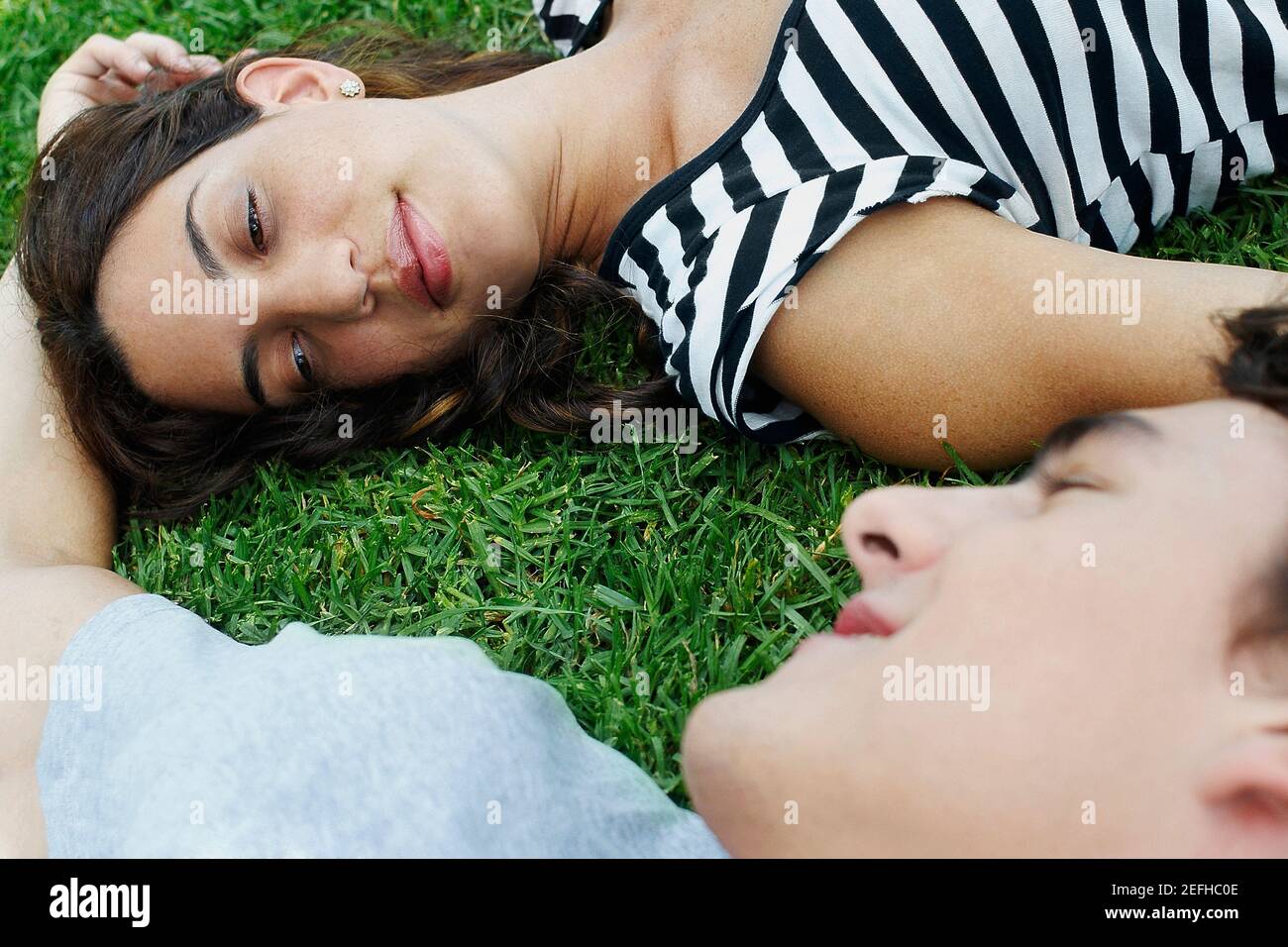 Vista ad alto angolo di una giovane coppia sdraiata sul erba in un parco Foto Stock