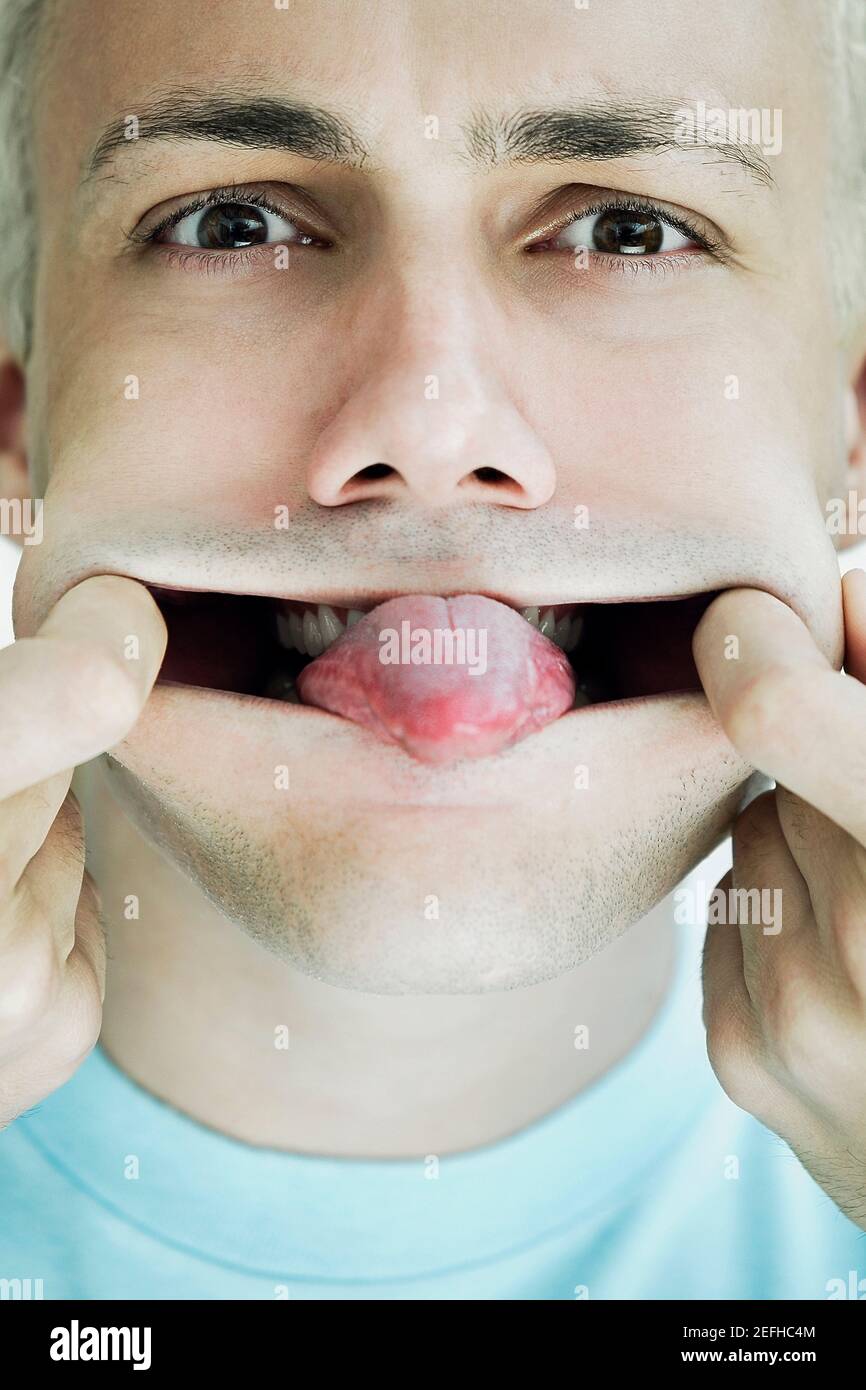 Ritratto di un giovane che allunga la bocca e si attacca la sua lingua fuori Foto Stock