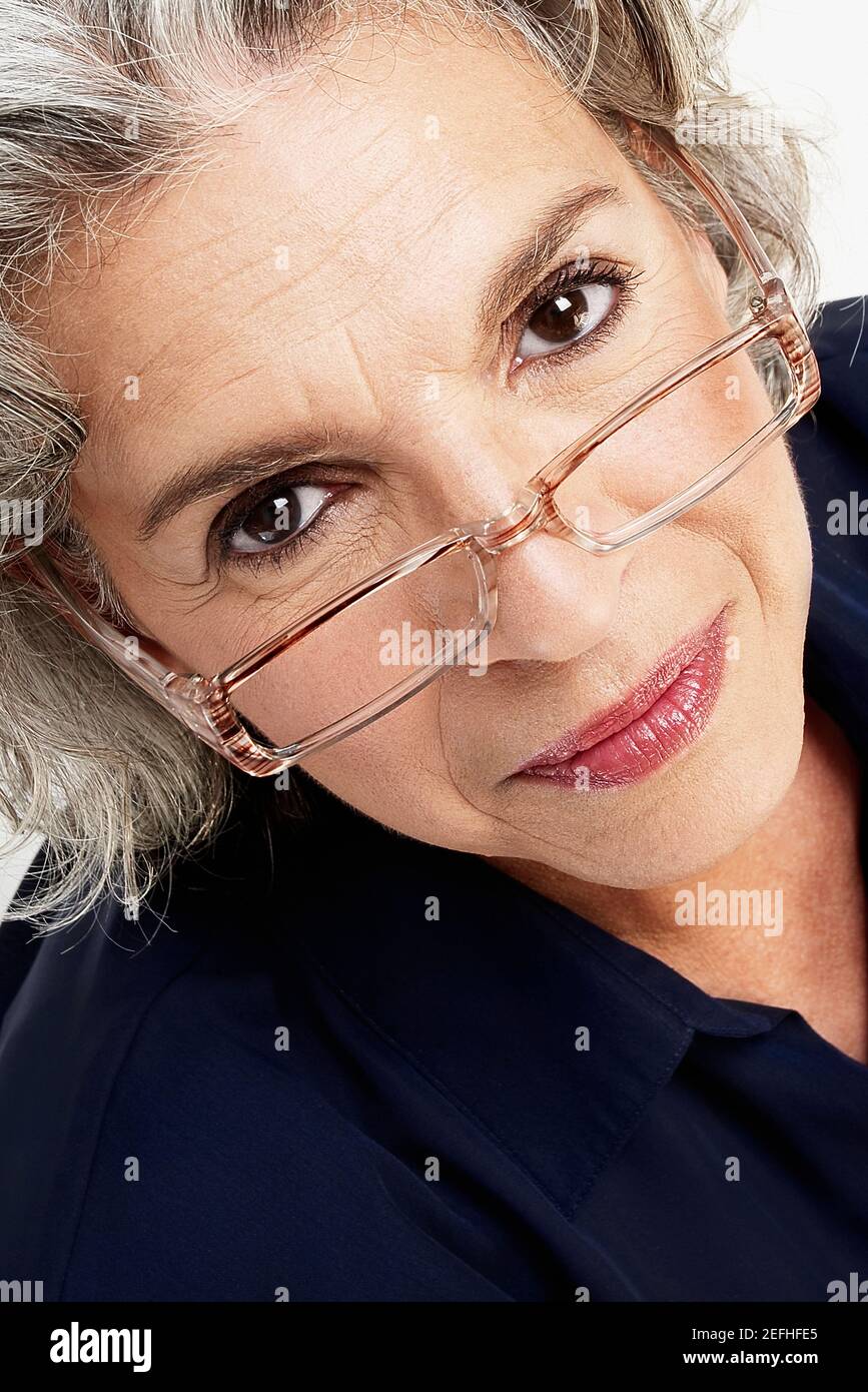 Ritratto di una donna matura che sbirciava sugli occhiali Foto Stock