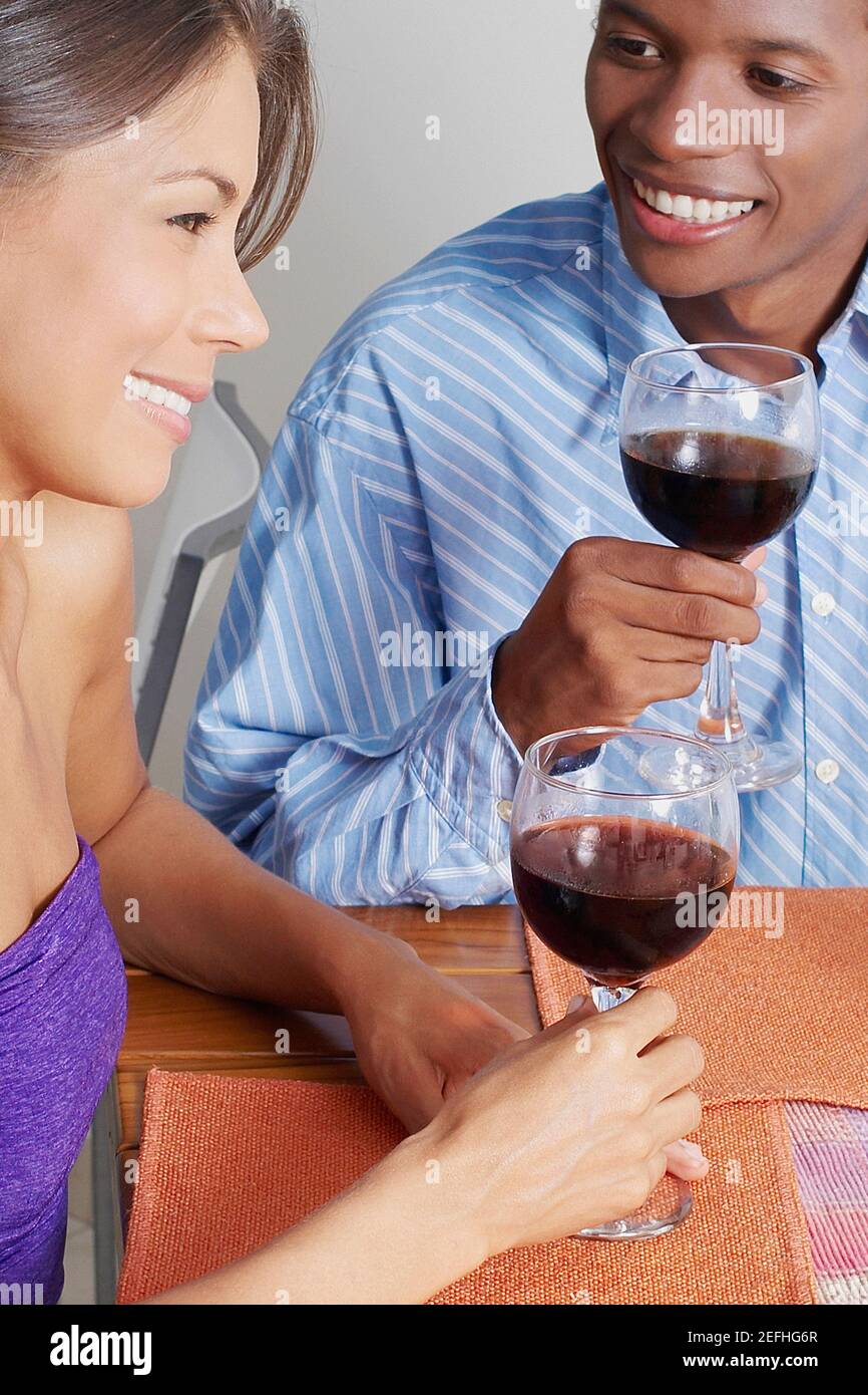 Primo piano di una giovane coppia seduta e che tiene bicchieri di vino Foto Stock