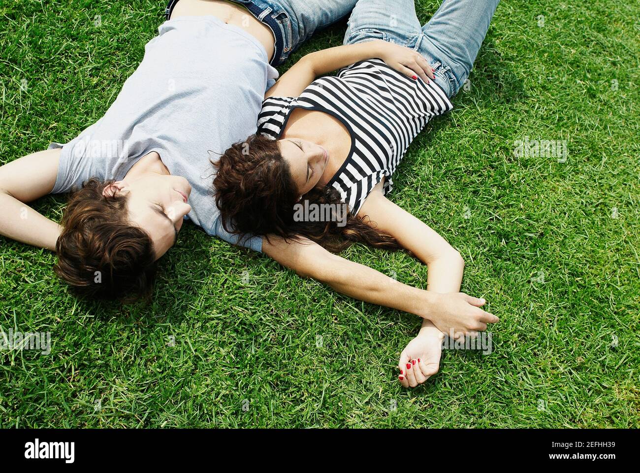 Vista ad alto angolo di una giovane coppia sdraiata sul erba in un parco Foto Stock