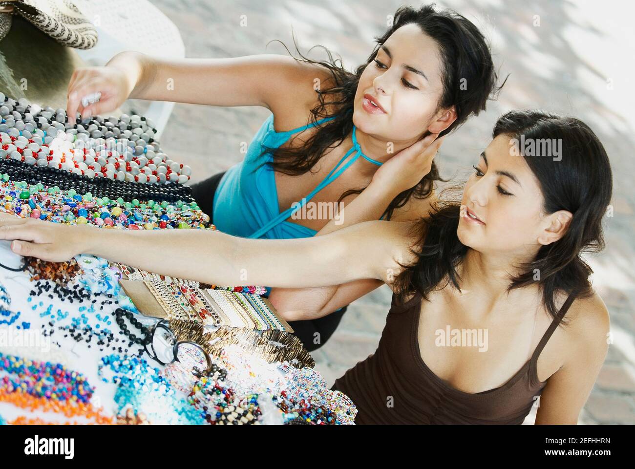 Vista ad alto angolo di due giovani donne sedute a un stallo del mercato Foto Stock