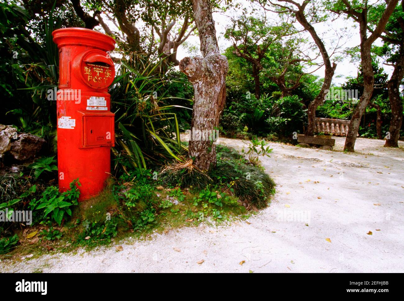 Casella postale rossa lungo un passaggio, Taketomi, Ryukyus, Giappone Foto Stock