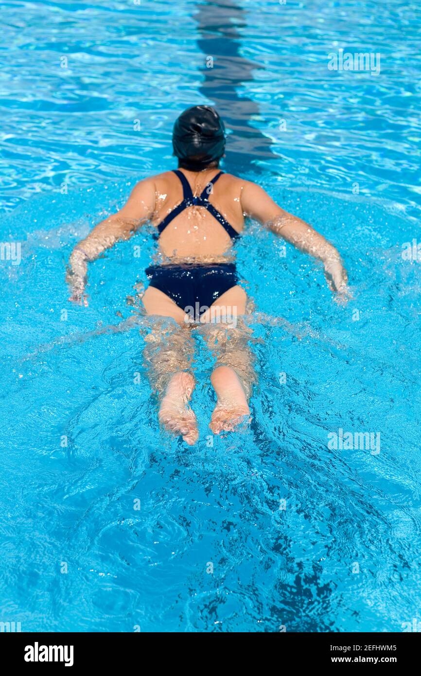 Vista posteriore di una giovane donna che nuota in una nuotata piscina Foto Stock