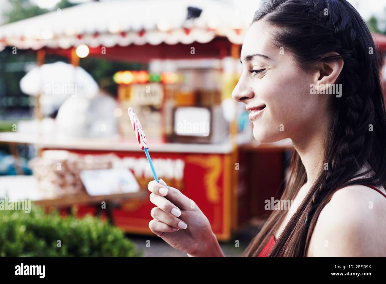 Profilo laterale di una giovane donna che tiene un lollipop Foto Stock