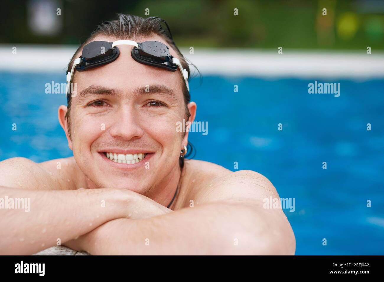 Primo piano di un uomo medio adulto che si appoggia al bordo di una piscina Foto Stock