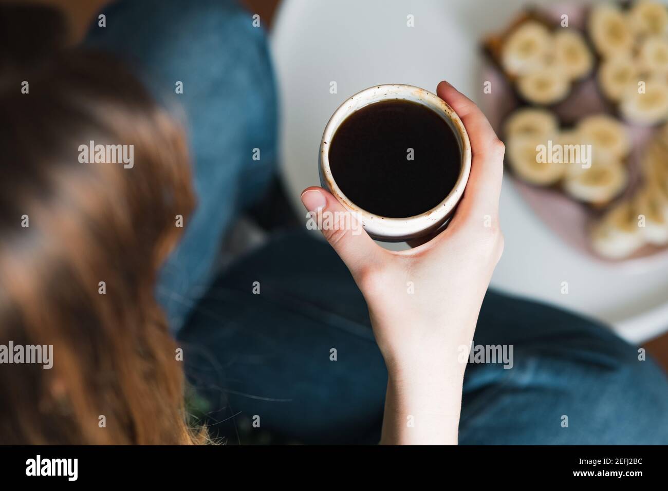 Donna tiene una tazza di caffè nero, colpo candida. Dopo la colazione, bere il caffè del mattino a casa Foto Stock