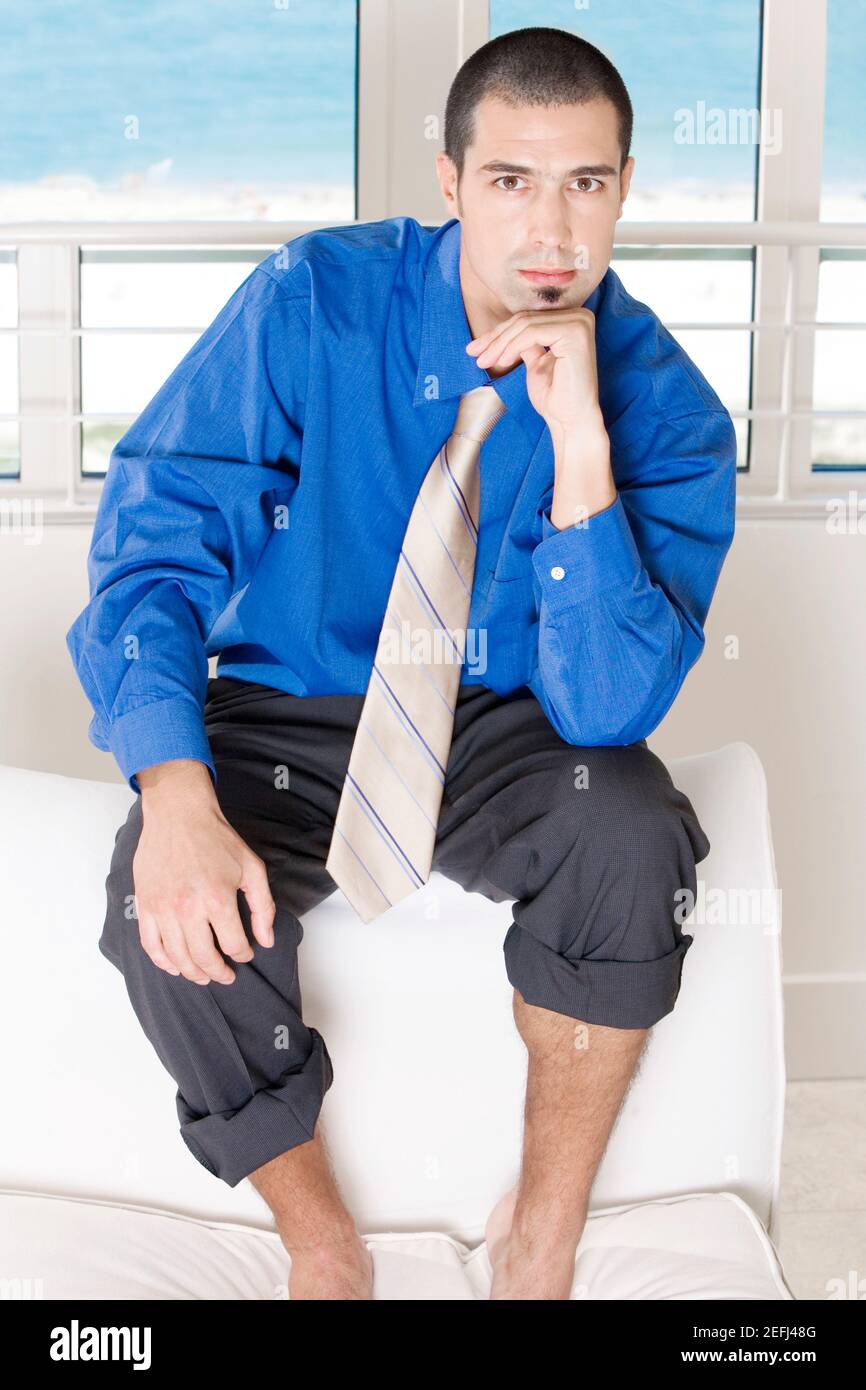 Ritratto di un uomo d'affari seduto su un divano con il suo pantaloni arrotolati Foto Stock
