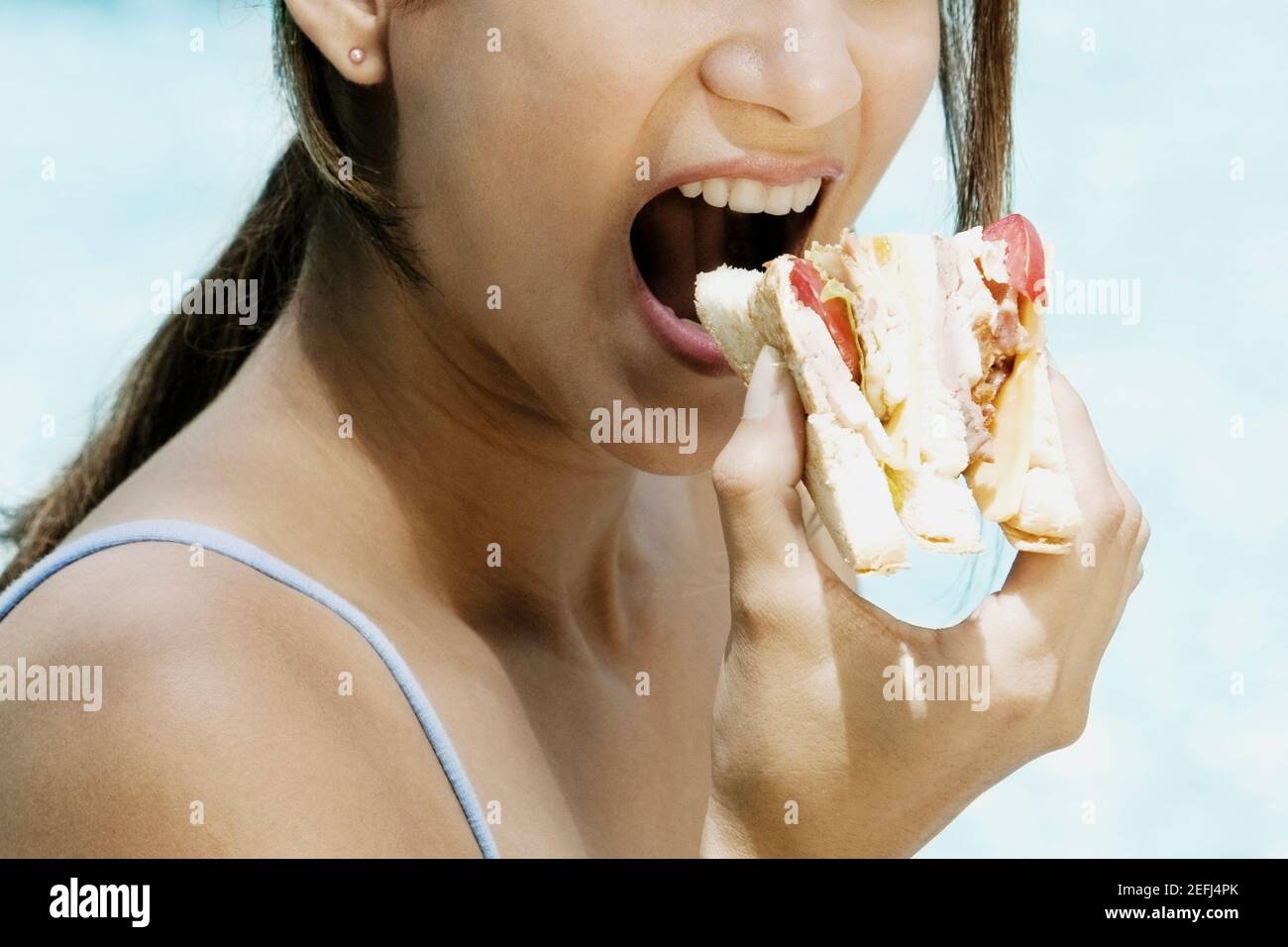 Primo piano di una giovane donna che mangia un panino di formaggio di pomodoro Foto Stock
