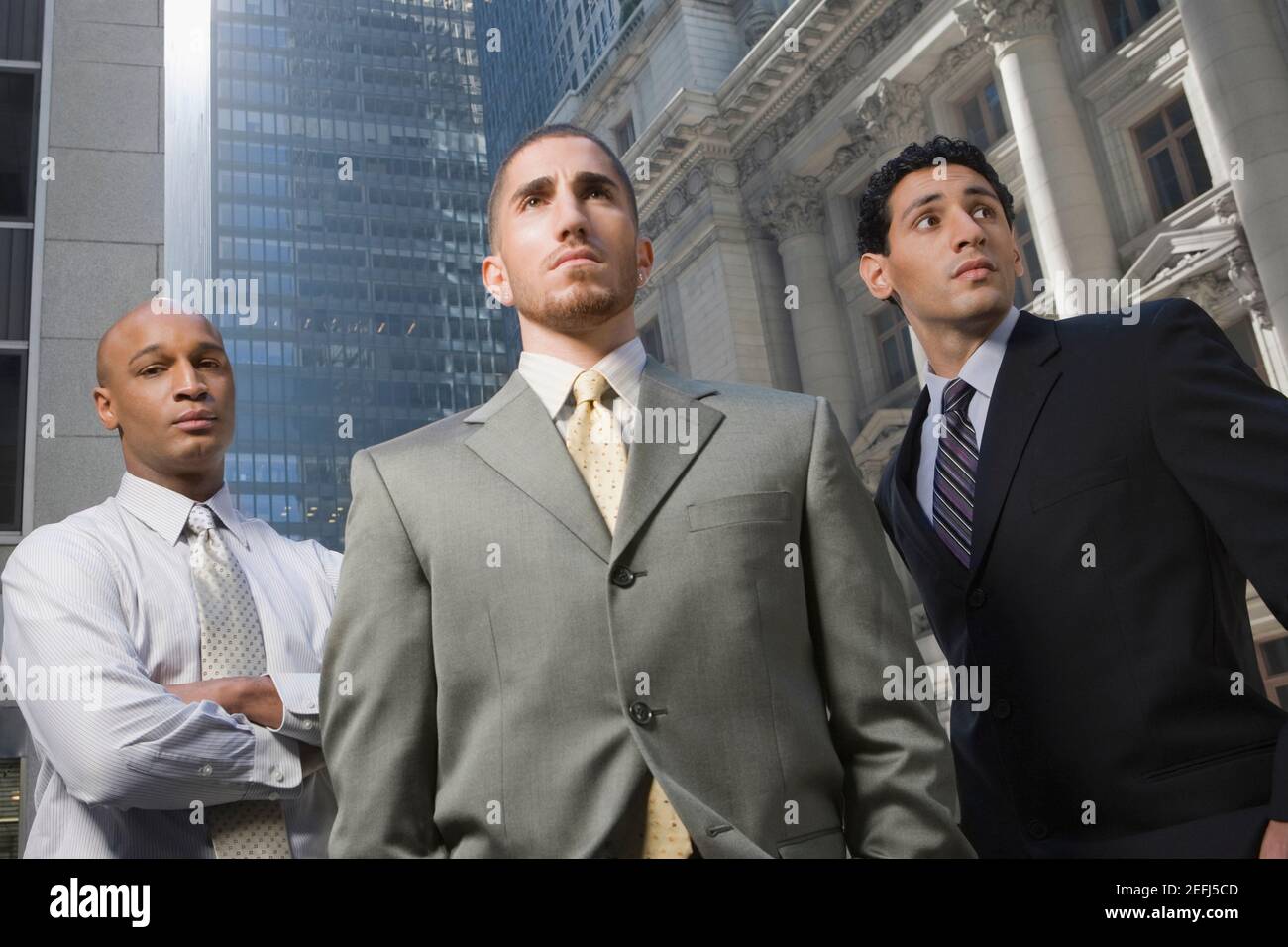 Vista ad angolo basso di tre uomini d'affari in piedi Foto Stock