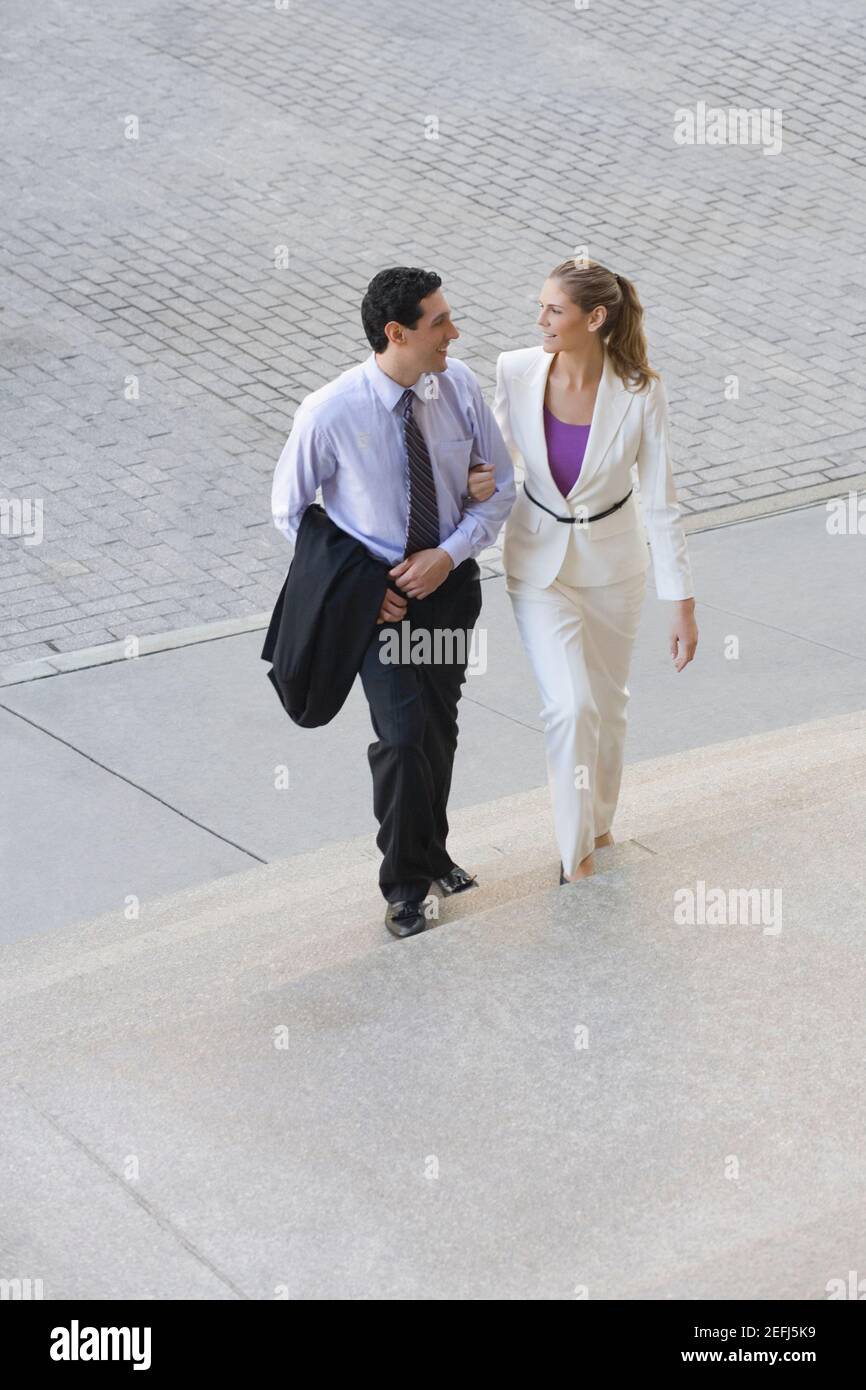 Uomo d'affari e una donna d'affari che si muove su passi con il loro penetratore nel braccio Foto Stock