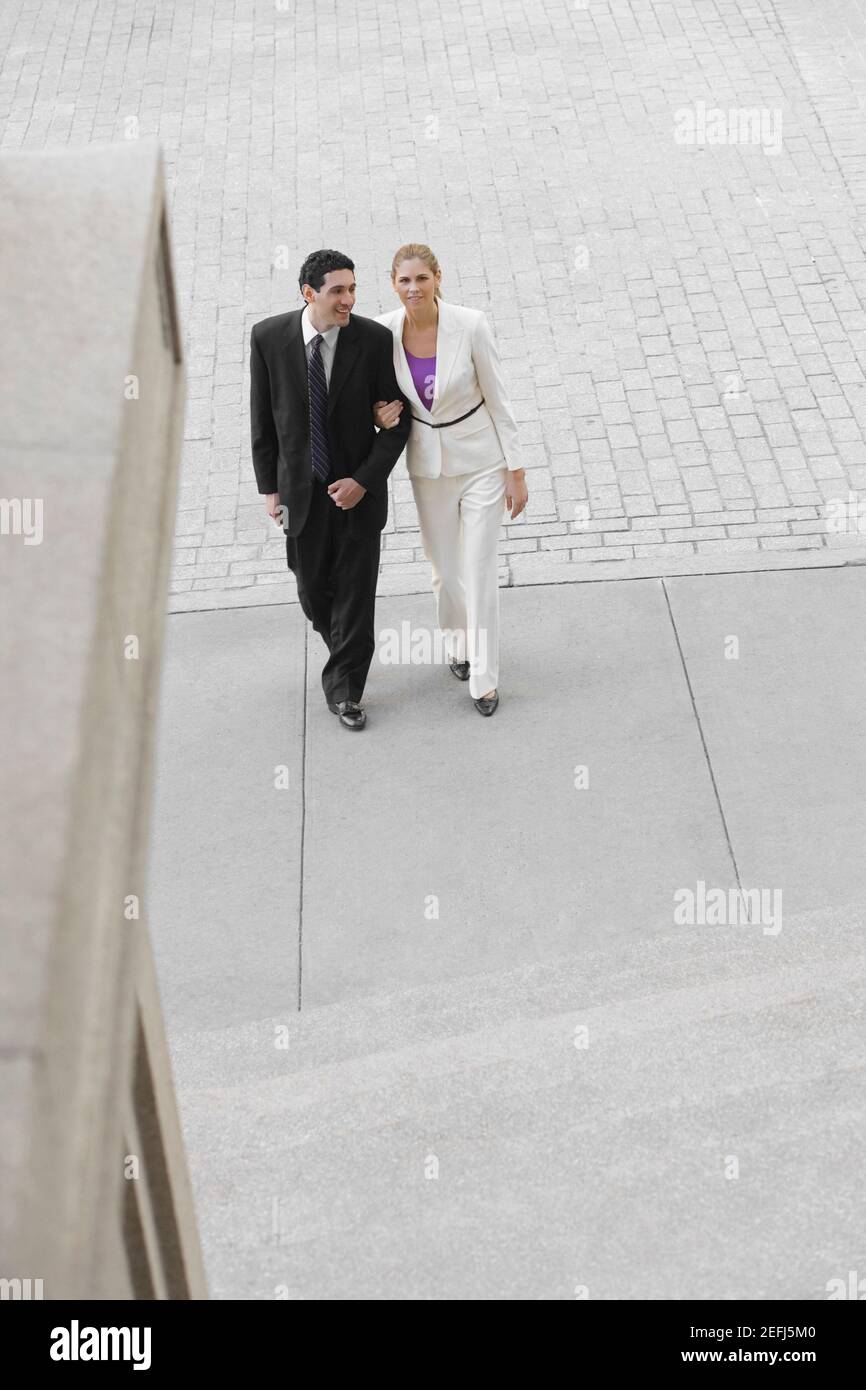 Uomo d'affari e una donna d'affari che cammina con il braccio nel braccio Foto Stock