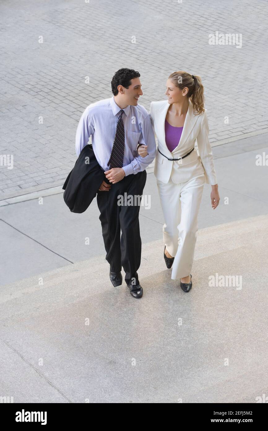 Uomo d'affari e una donna d'affari che si muove su passi con il loro penetratore nel braccio Foto Stock
