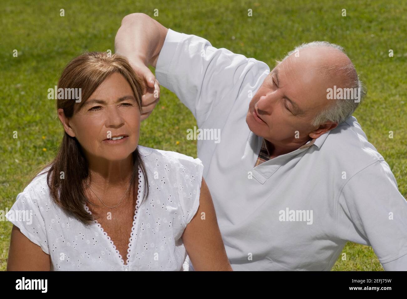 Uomo anziano che regola i capelli di una donna anziana Foto Stock