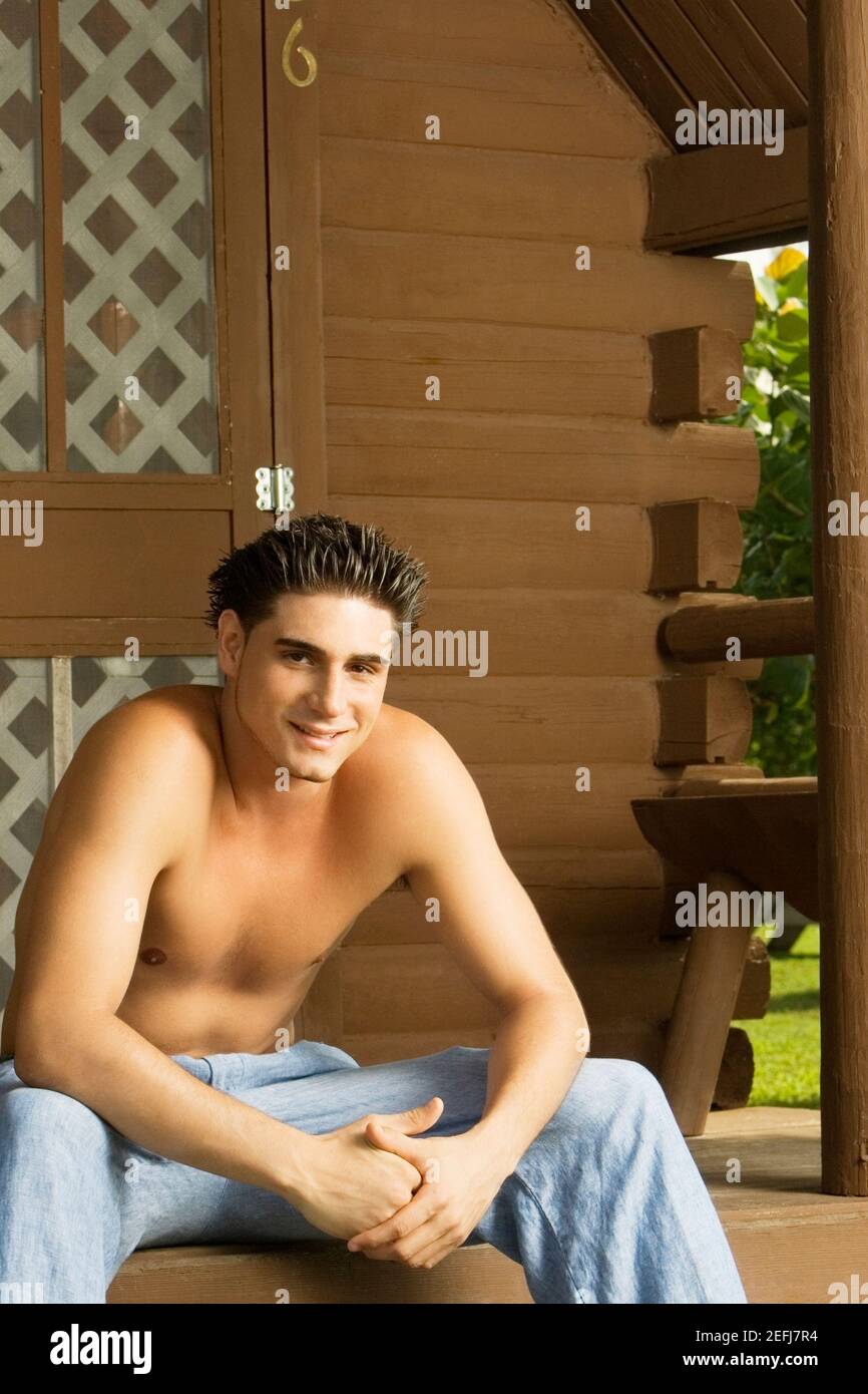 Ritratto di un giovane nudo seduto sul portico e sorridente Foto Stock