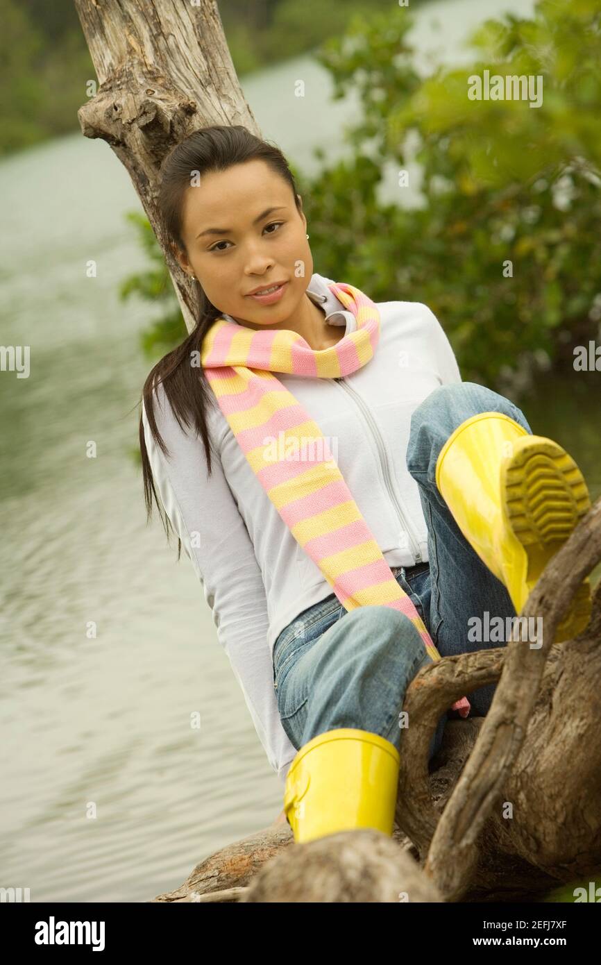 Ritratto di una giovane donna seduta su un tronco d'albero vicino al lago Foto Stock