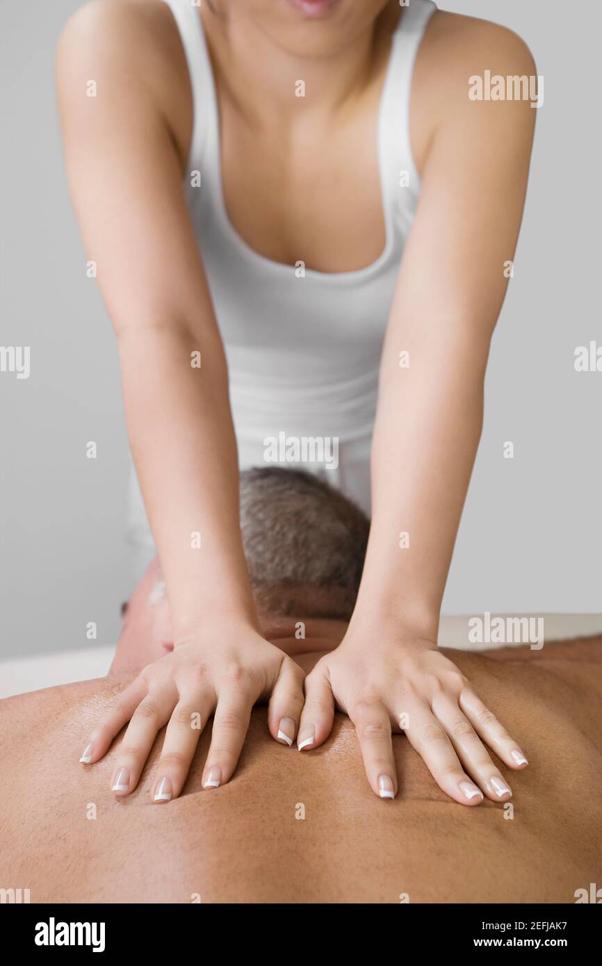 Vista posteriore di un uomo anziano che riceve un massaggio alla schiena da un massaggiatore Foto Stock