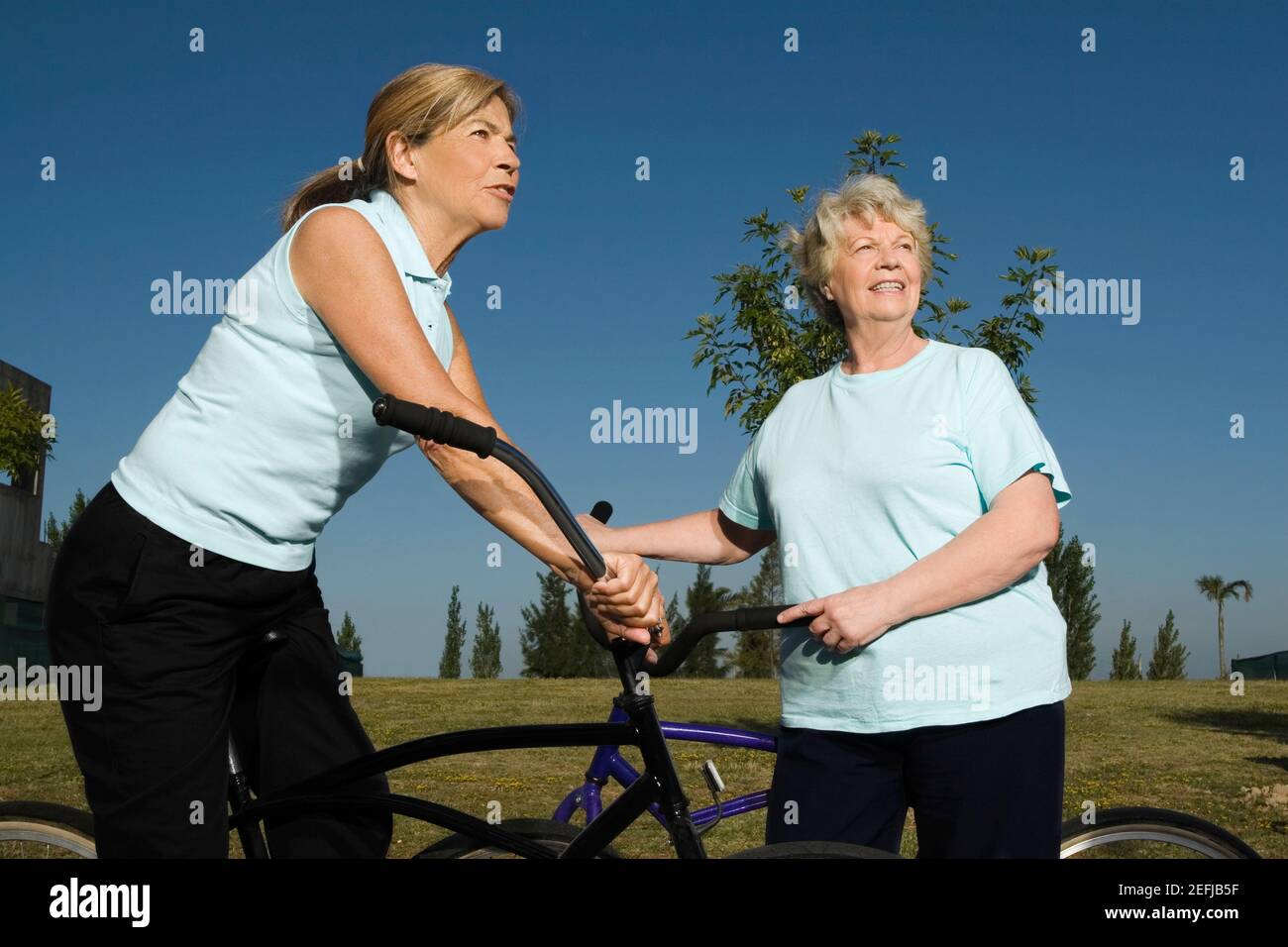 Due donne senior in piedi con biciclette Foto Stock