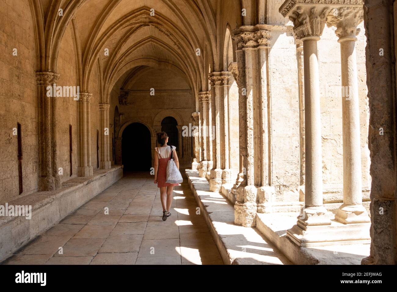 Giovane turista che visita il chiostro della cattedrale di Arles, Francia, in estate Foto Stock