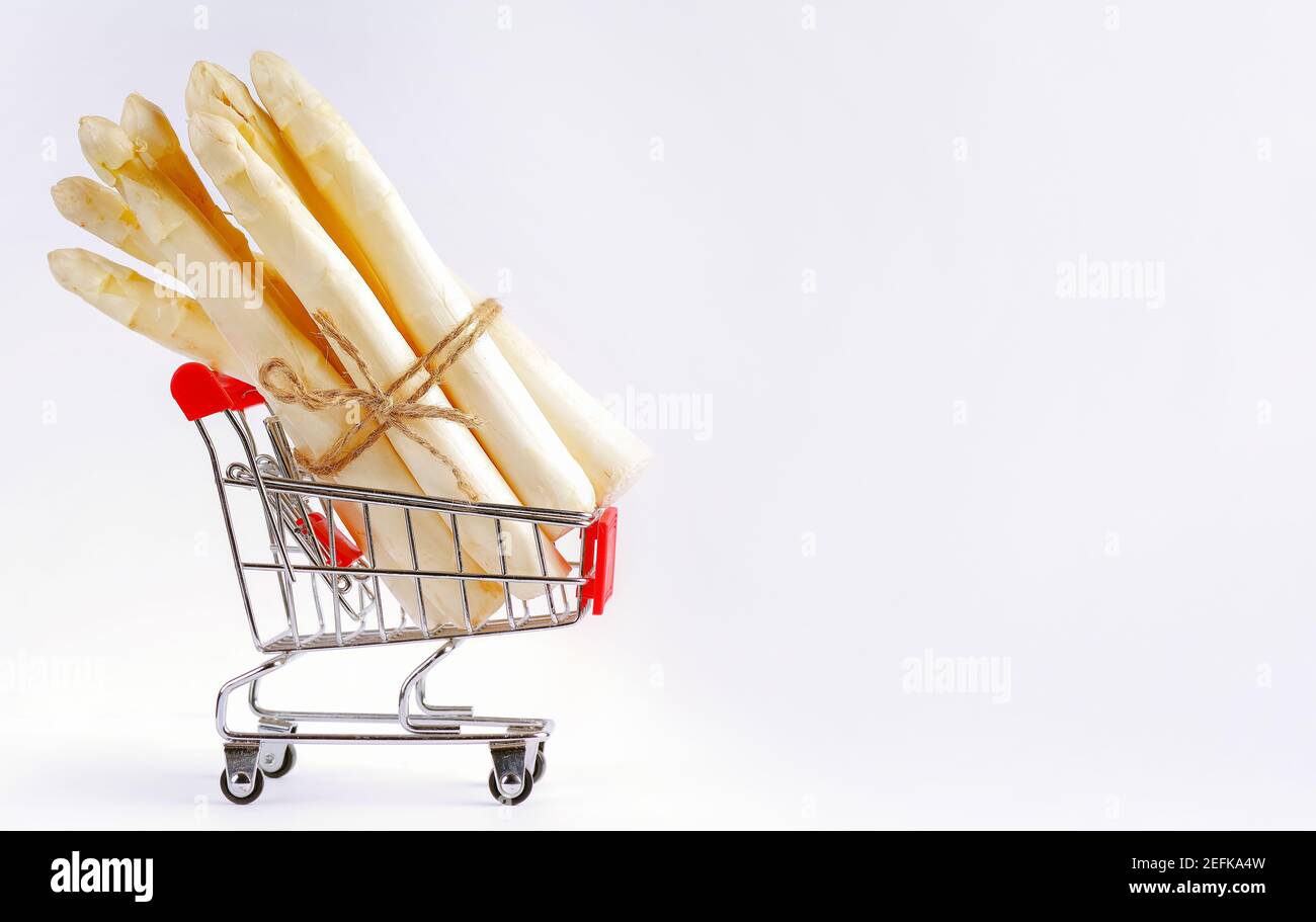Asparagi bianchi in un carrello di supermercato su uno sfondo chiaro. Asparagi bianchi, verdure, cibo sano. Asparagi bianchi organici appena raccolti b Foto Stock