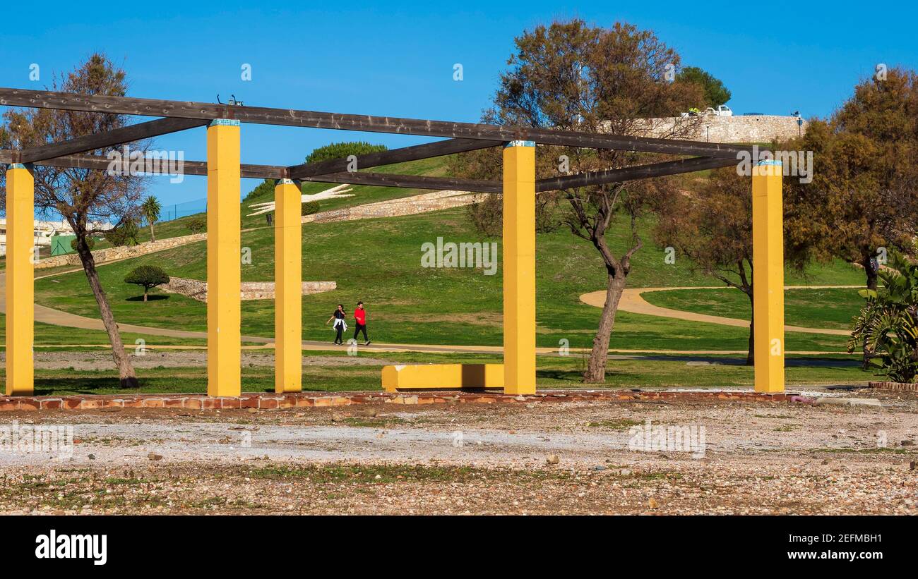 Fuengirola, Malaga, Spagna. 01/22/2021. Primo piano di un pergolato con colonne gialle nel parco del Castello di Sohail a Fuengirola, dove una coppia cammina Foto Stock