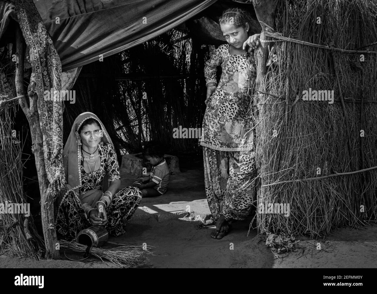 Madre, figlia, e toddler nella capanna di paglia di makeshift nel deserto che osserva desitute vicino Pushkar, Rajasthan, India. Foto Stock