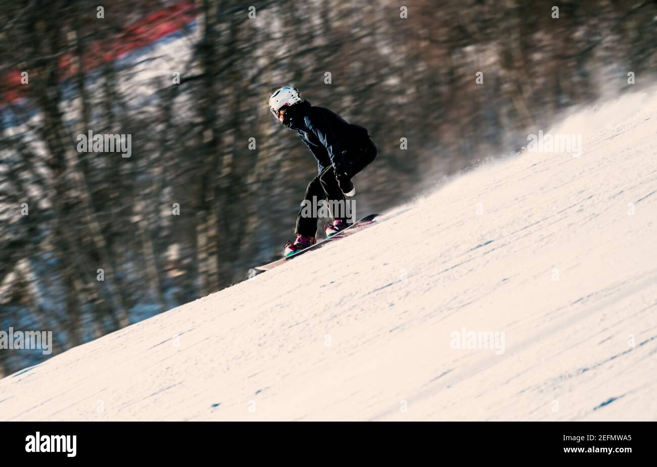 Snowboarder femminile che scende su una ripida pendenza in una giornata invernale. Foto Stock