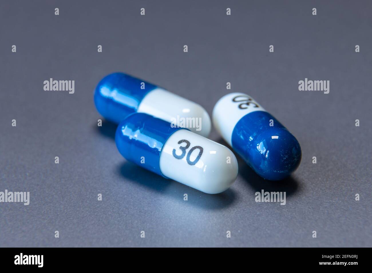 Compresse blu e bianche su sfondo grigio. Assistenza sanitaria. Foto Stock