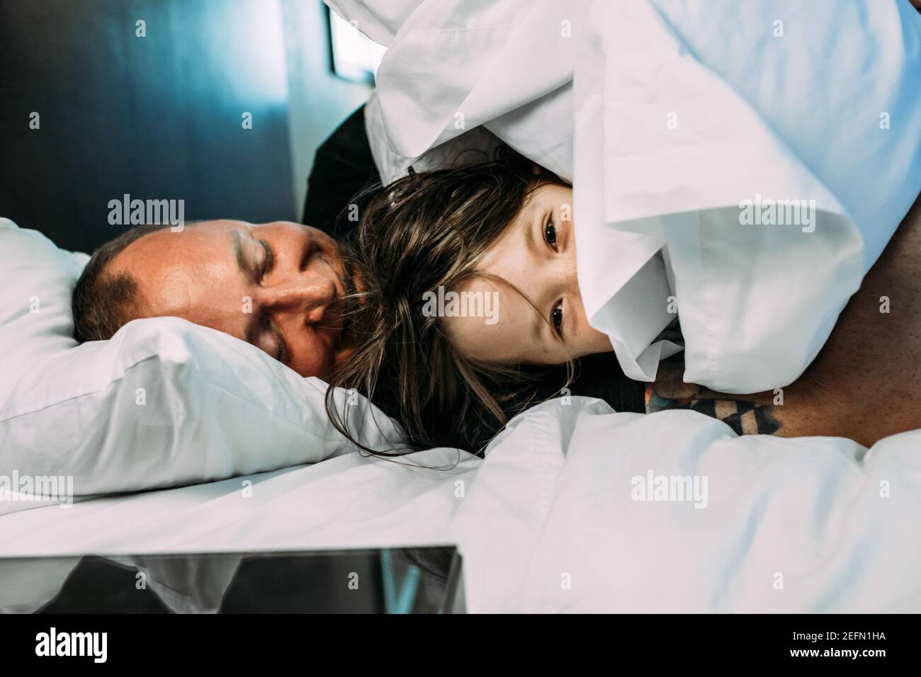 Papà felice e bambino piccolo che si snaffata su un letto sorridente Foto Stock