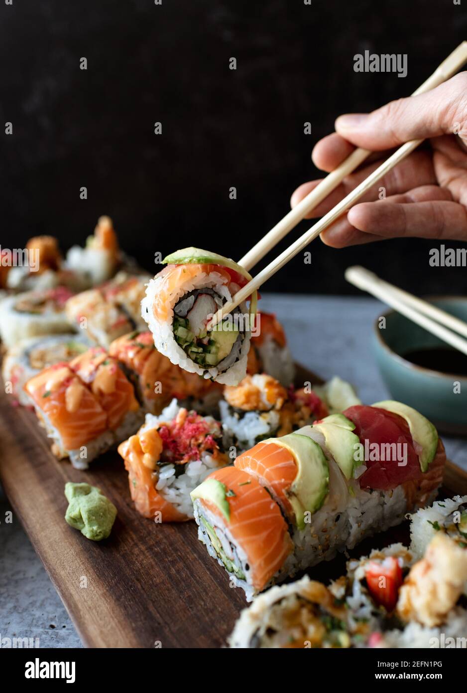 Utilizzare le bacchette per raccogliere un sushi roll off di un piatto. Foto Stock
