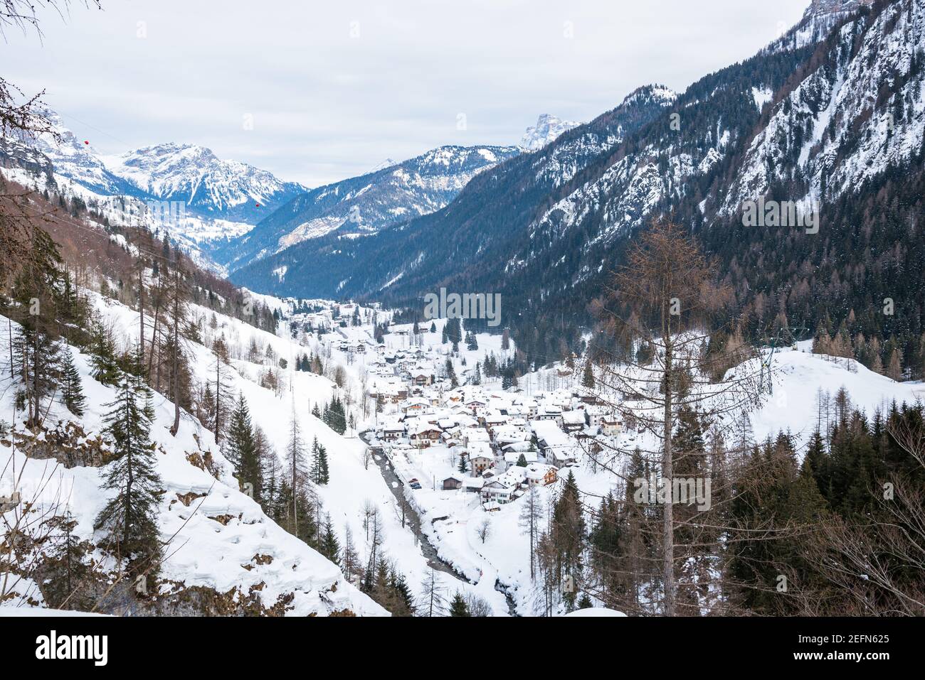 Vista di una città in fondo a una montagna valle coperta di neve in una giornata invernale nuvolosa Foto Stock