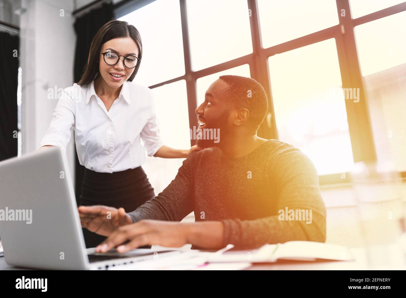 Colleghi giovani ed eterogenei che lavorano con pc in ufficio Foto Stock