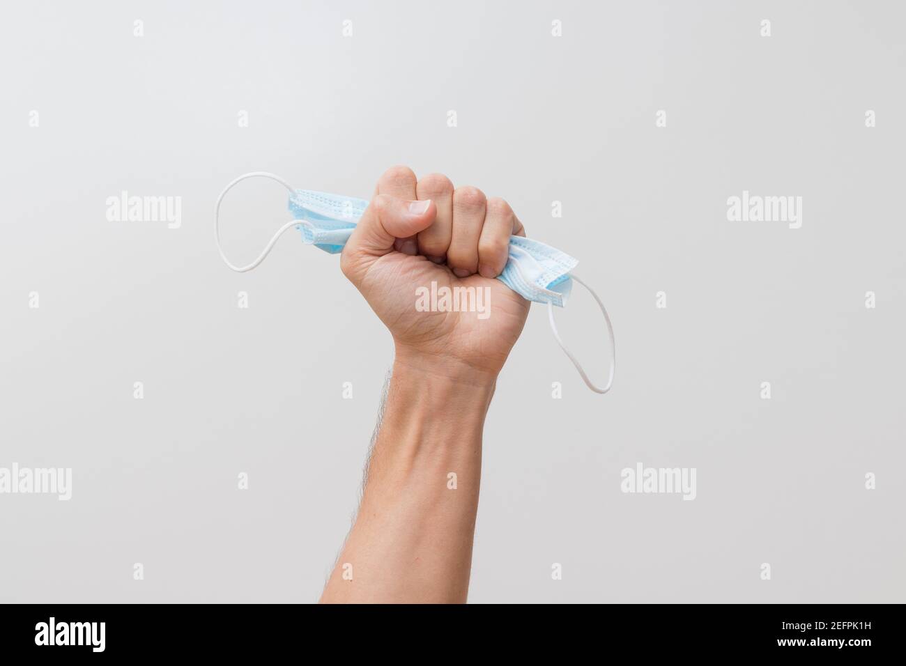 Schiacciamento della mano maschera chirurgica o igienica che mostra , movimento anti maschera, fine della covid o lotta contro covid 19 su sfondo bianco. Foto Stock
