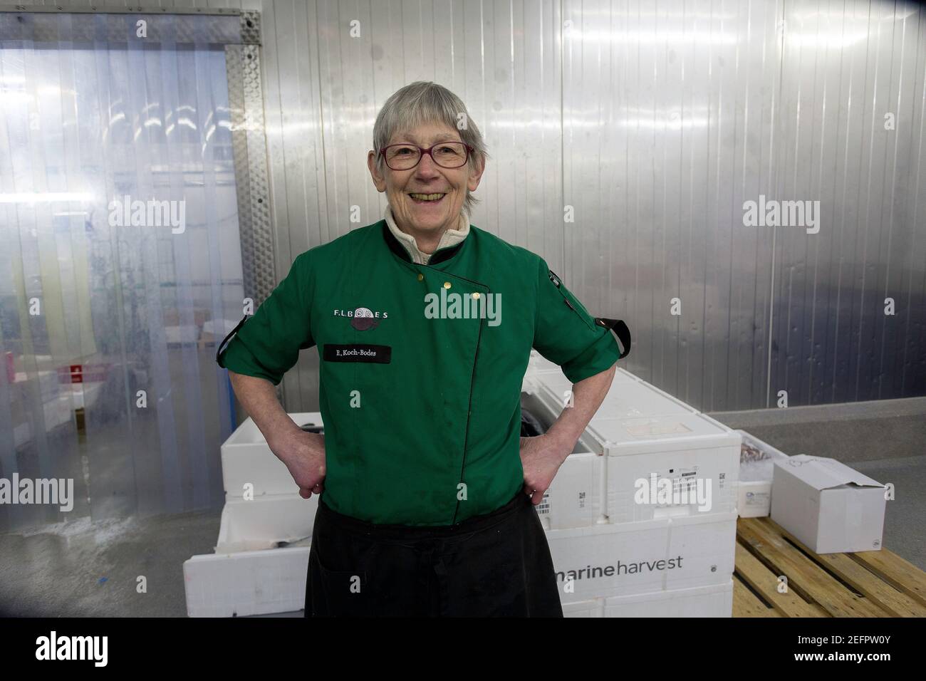 Ritratto di una felice donna matura pescatrice in piedi in lei sala di lavoro con braccia sui fianchi Foto Stock