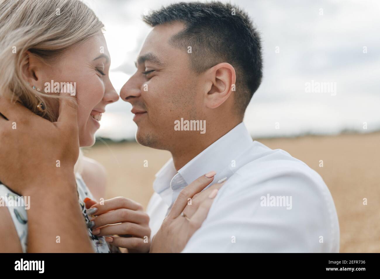 Uomo e donna baciando sullo sfondo di un campo. Coppia felice in un campo di grano Foto Stock
