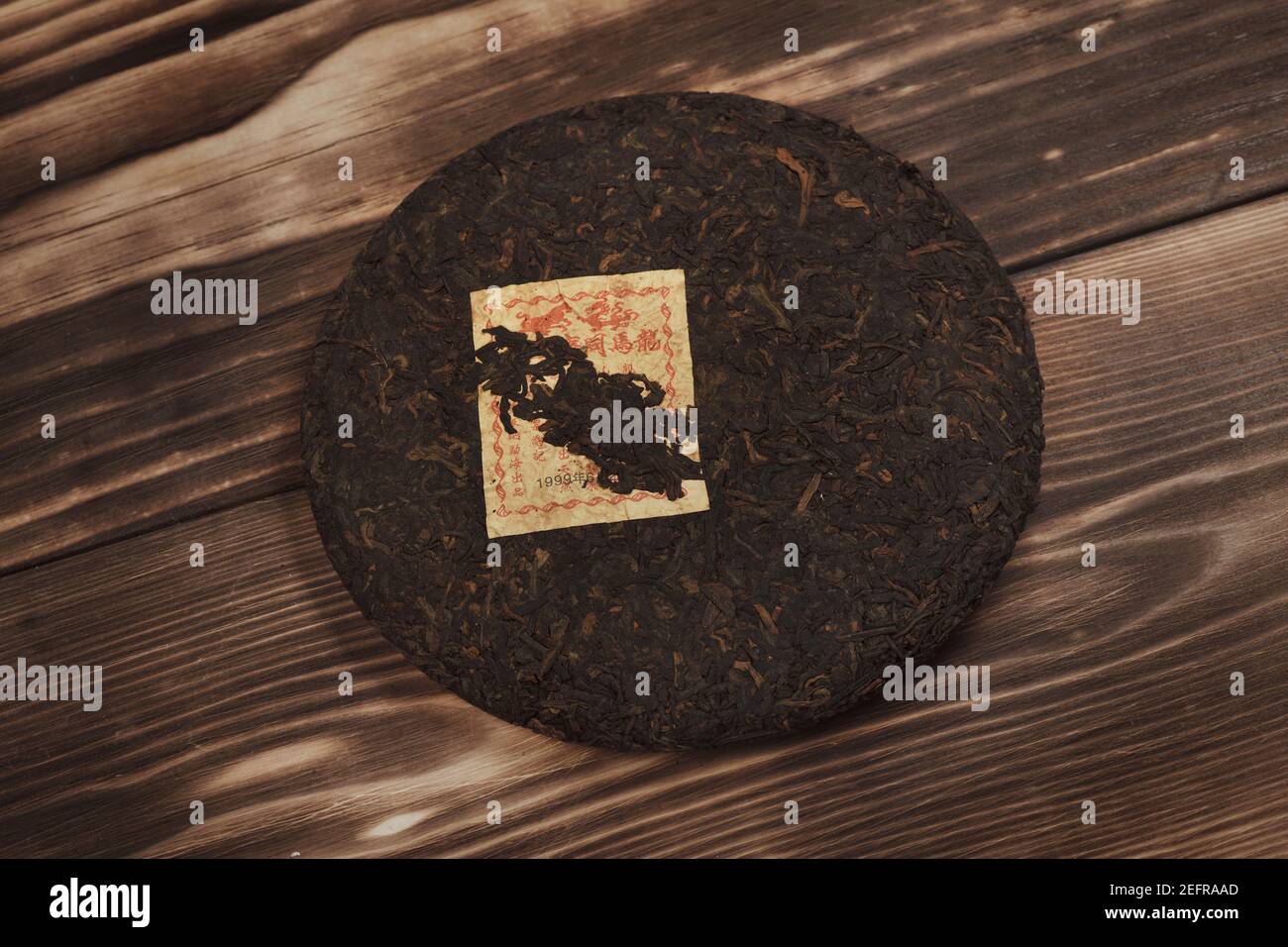 Pu'er o pu-erh, tè cinese fermentato pressato a forma di disco. Tè nero maturato cinese, vita artistica morta su sfondo di tavola di legno scuro. Più puro Foto Stock