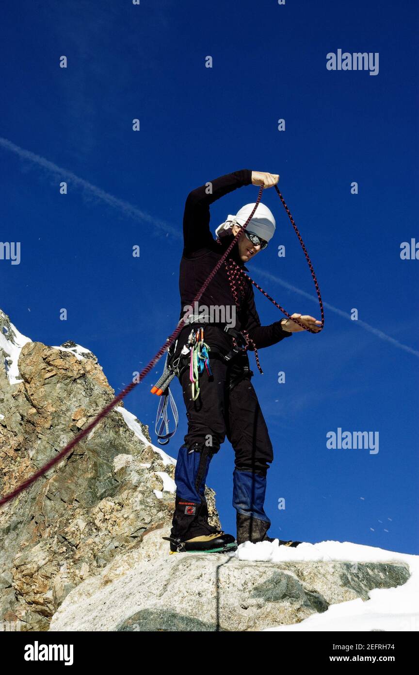 Un alpinista che si avvita corda alta su un picco nel alpi francesi Foto Stock