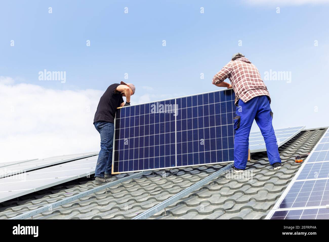 pannelli solari. Gli ingegneri elettrici mans stanno lavorando installando pannelli solari sulla stazione solare sul tetto della casa contro il cielo blu. Sviluppo sole alternati Foto Stock