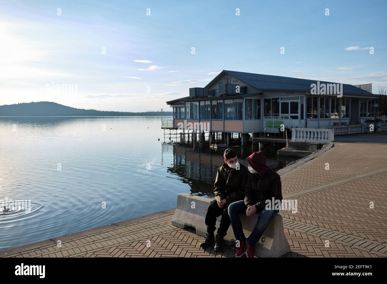 due amici chiacchierano davanti a uno chalet sul lago con la maschera anti-covid19 Foto Stock