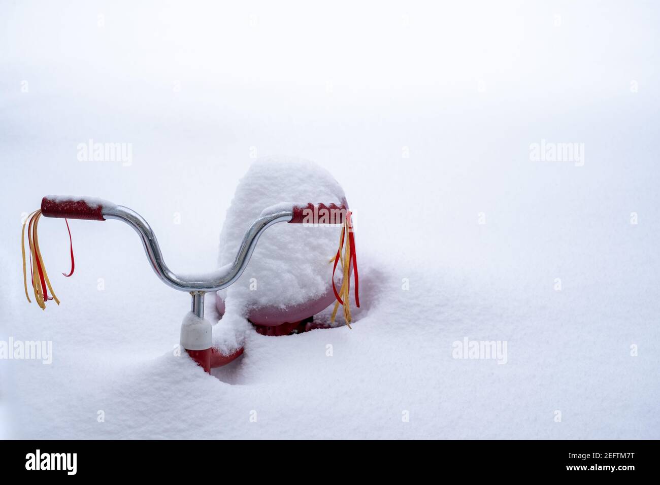 Un triciclo con le ruscelli del manubrio è quasi sepolto nella neve profonda dopo una nevicata pesante. Foto Stock