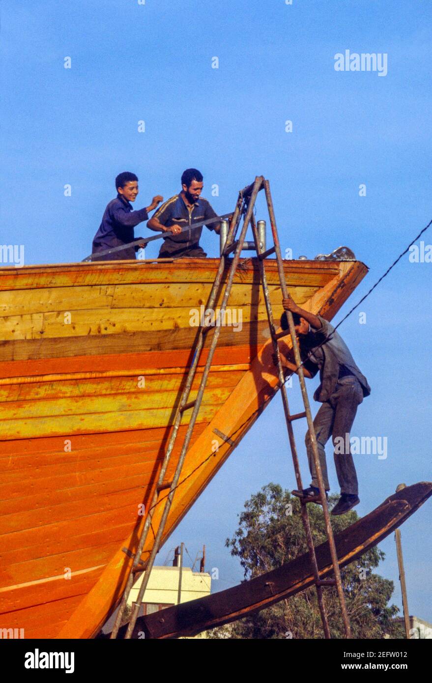 Tre uomini che lavorano su una barca nel cantiere, Agadir, Marocco, 1987. Foto Stock