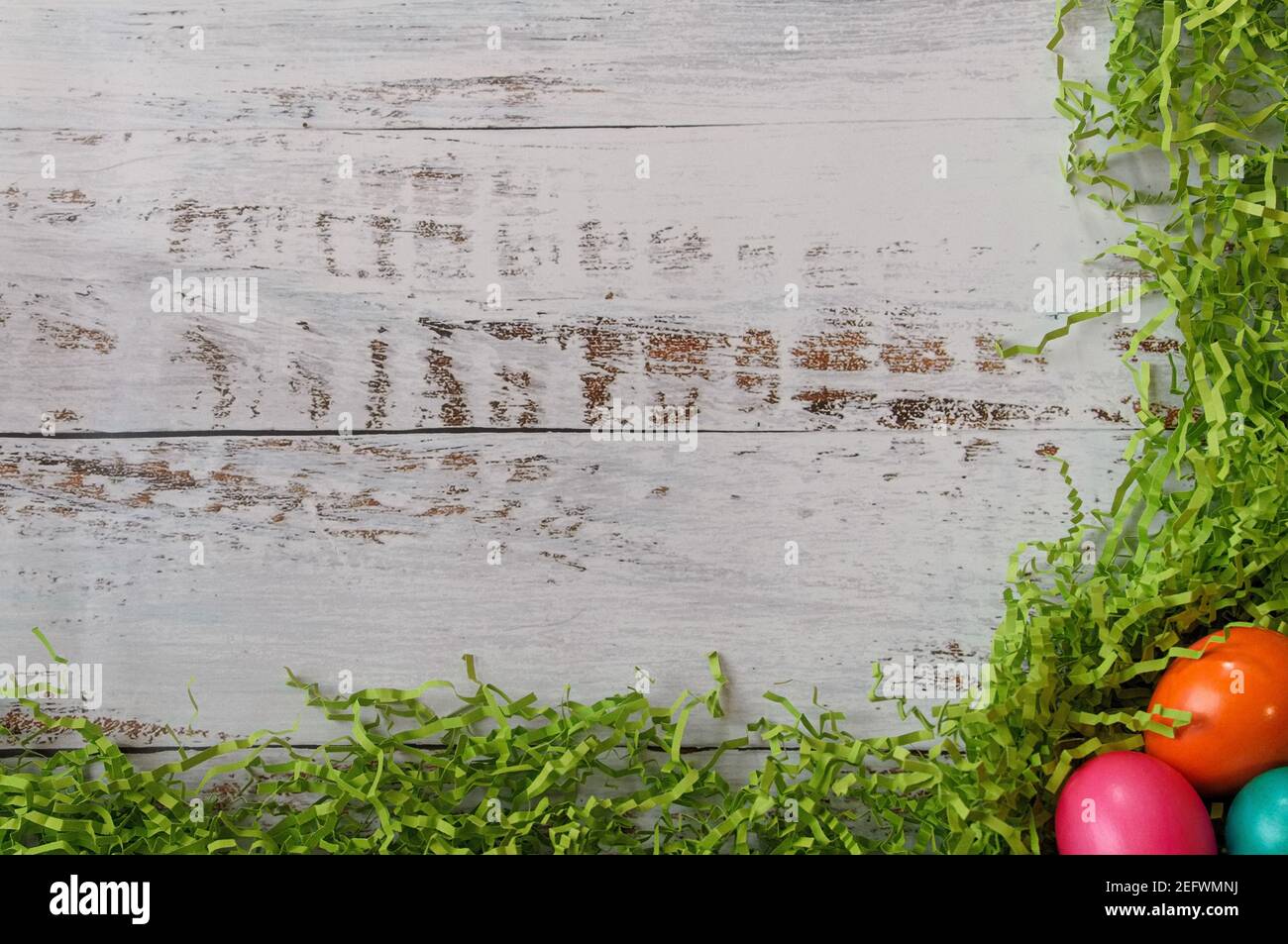 Tre uova di pasqua colorate nell'angolo in basso a destra con verde erba pasquale lungo il confine, con spazio per la copia Foto Stock