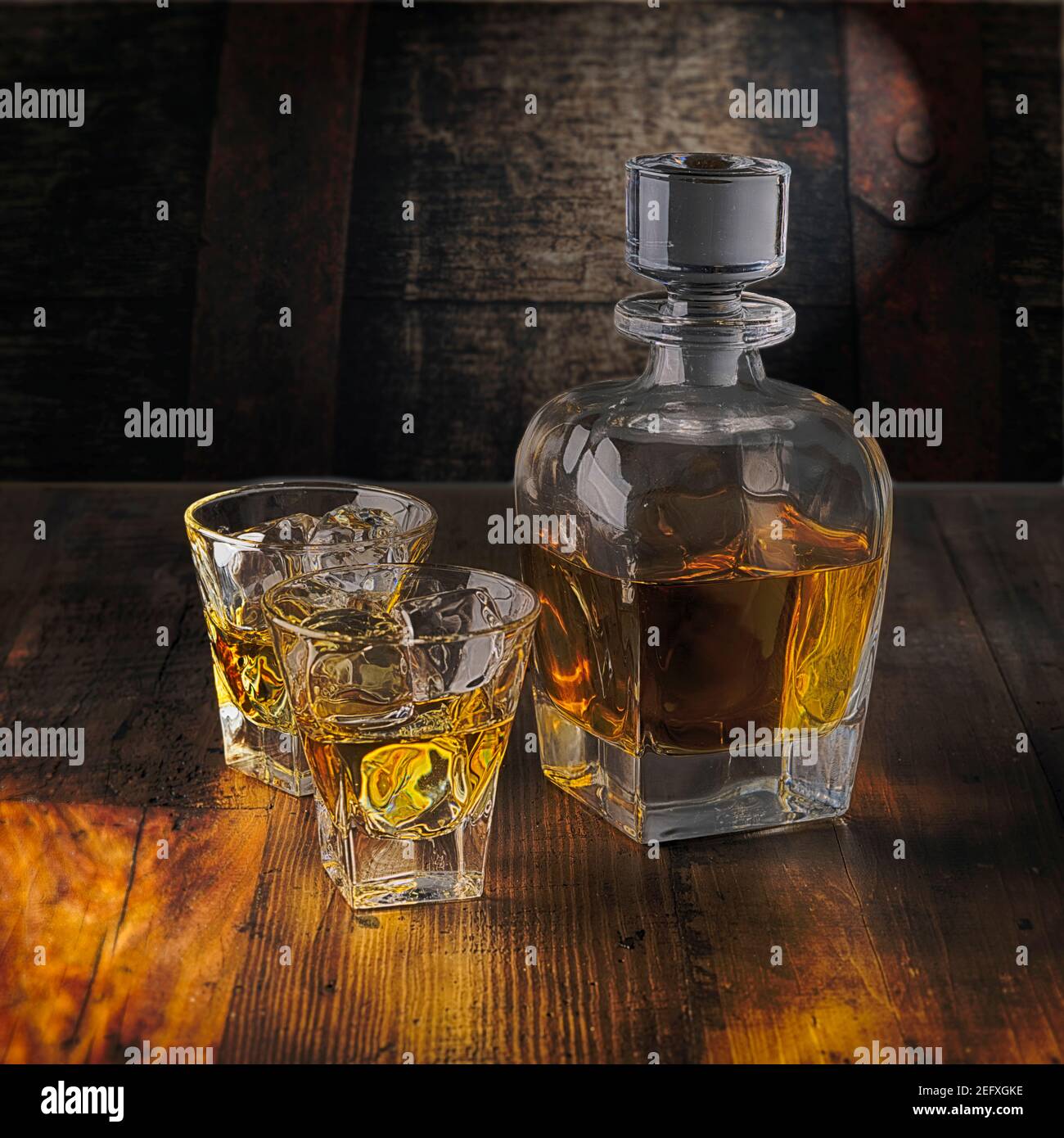 Una bottiglia di whiskey e due bicchieri sulle rocce Un tavolo di legno Foto Stock